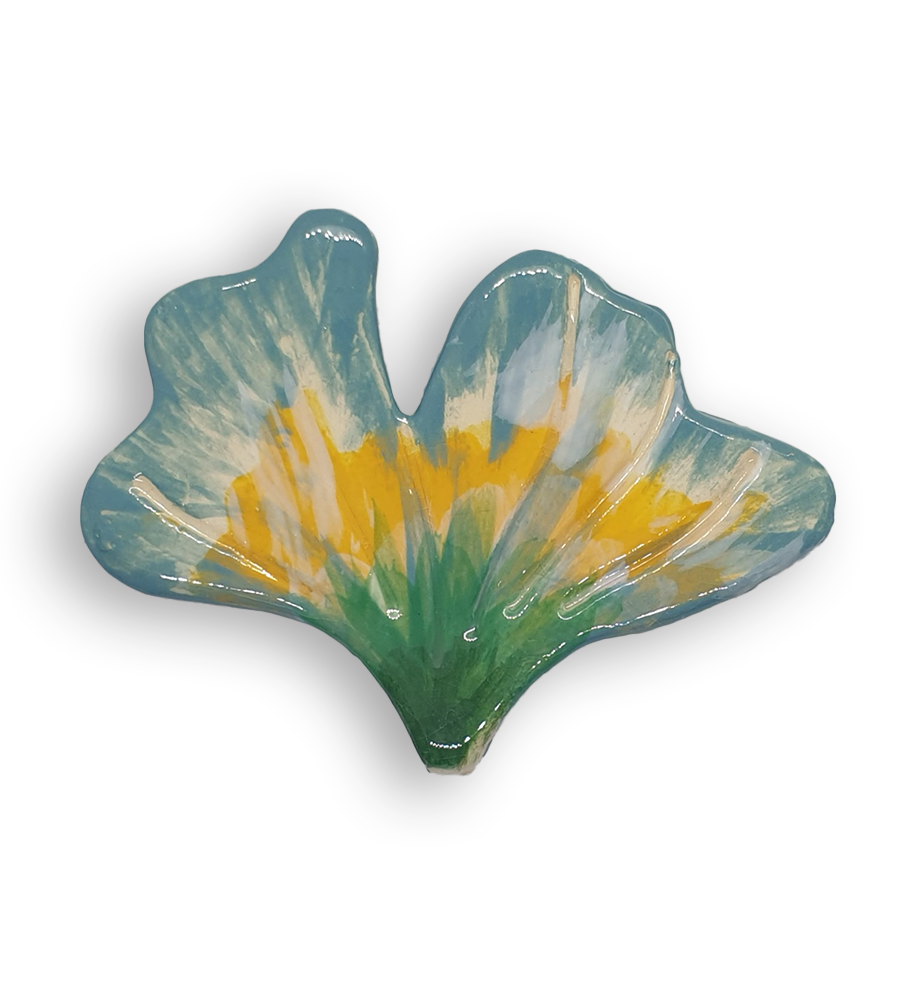 A hand-painted flower petal ceramic mosaic insert with green, yellow, blue and cream colours.