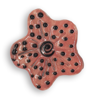 A hand-painted coral pink anemone ceramic mosaic insert with a black spiral at the centre, and a black dot design.