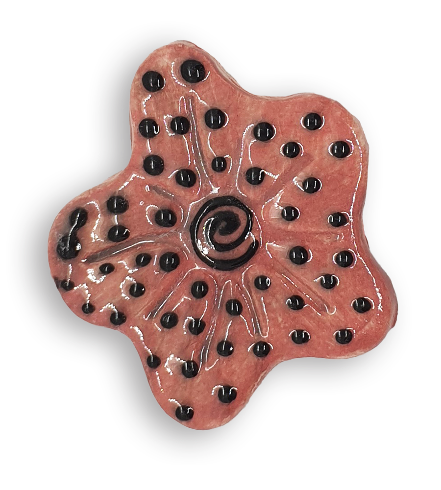 A hand-painted coral pink anemone ceramic mosaic insert with a black spiral at the centre, and a black dot design.