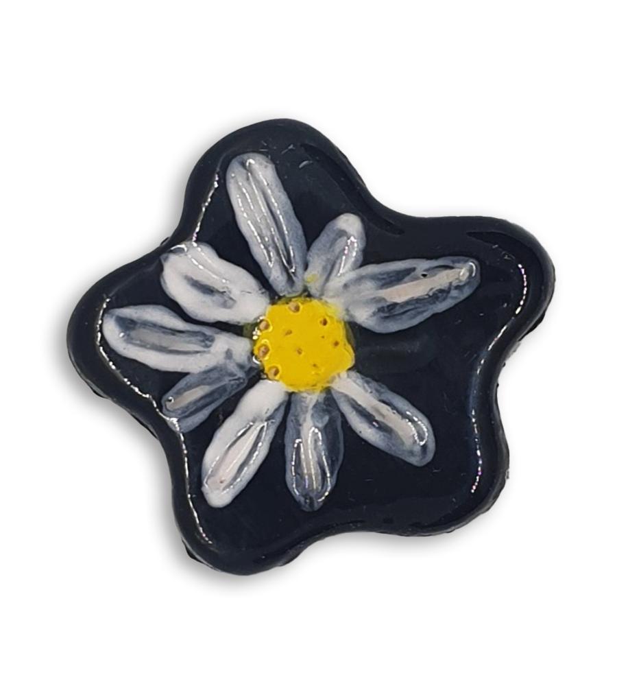 A simple black and white hand-painted anemone ceramic mosaic insert with a yellow centre.