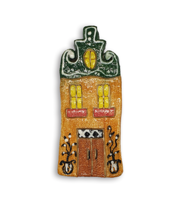 A hand-painted Dutch house ceramic mosaic insert with a green gabled roof.