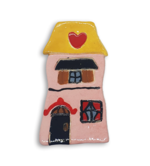 A hand-painted pink house ceramic mosaic insert with a heart design on the roof.