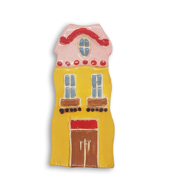 A hand-painted yellow Dutch house ceramic mosaic insert with a pink gabled roof.