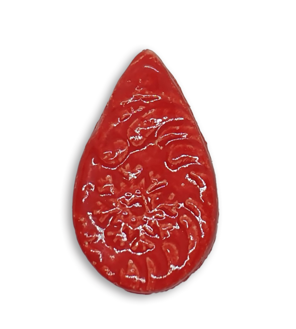 A red teardrop ceramic mosaic insert with a textured design.