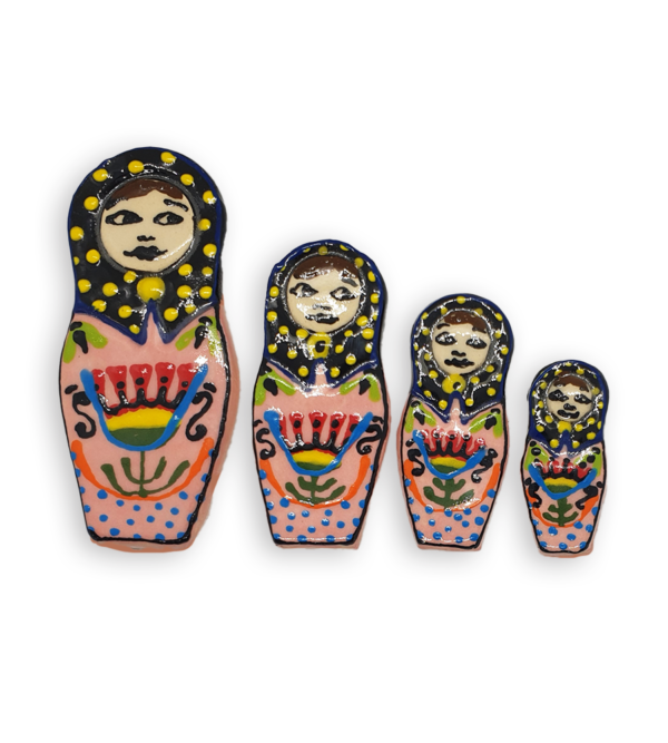 A set of four hand-painted Russian Doll ceramic mosaic inserts with pink dresses, black headscarves spotted with yellow and floral detail.