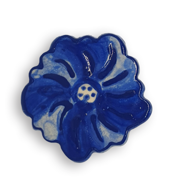 A ceramic mosaic insert in the shape of a dark blue poppy flower.