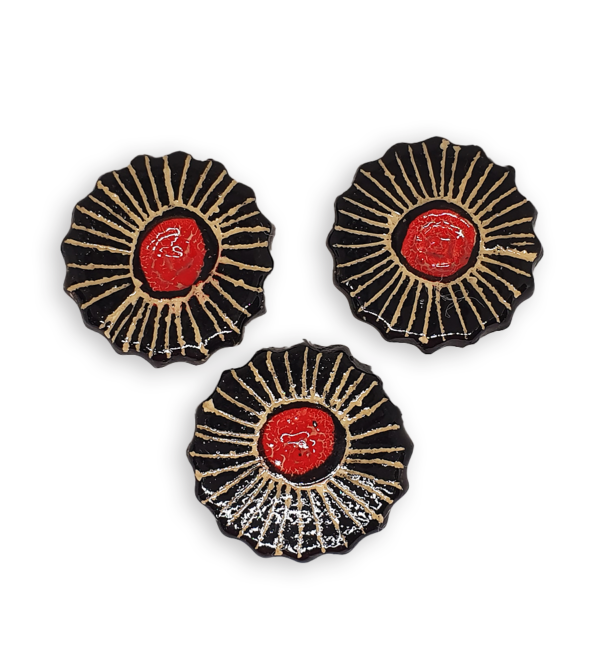 Three ceramic mosaic inserts in the shapes of black and red flowers.