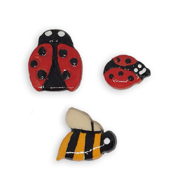 A selection of ceramic mosaic inserts in the shapes of ladybugs and bees.