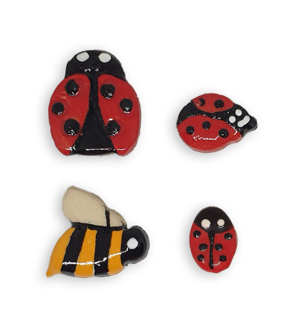 A selection of ceramic mosaic inserts in the shapes of ladybugs and bees.